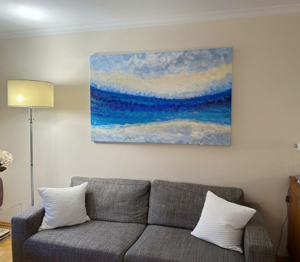 Painting in blue, white and gray hanging on a pale yellow wall.